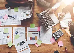 Zahlreiche Unterlagen un ein Laptop auf einem Schreibtisch. 